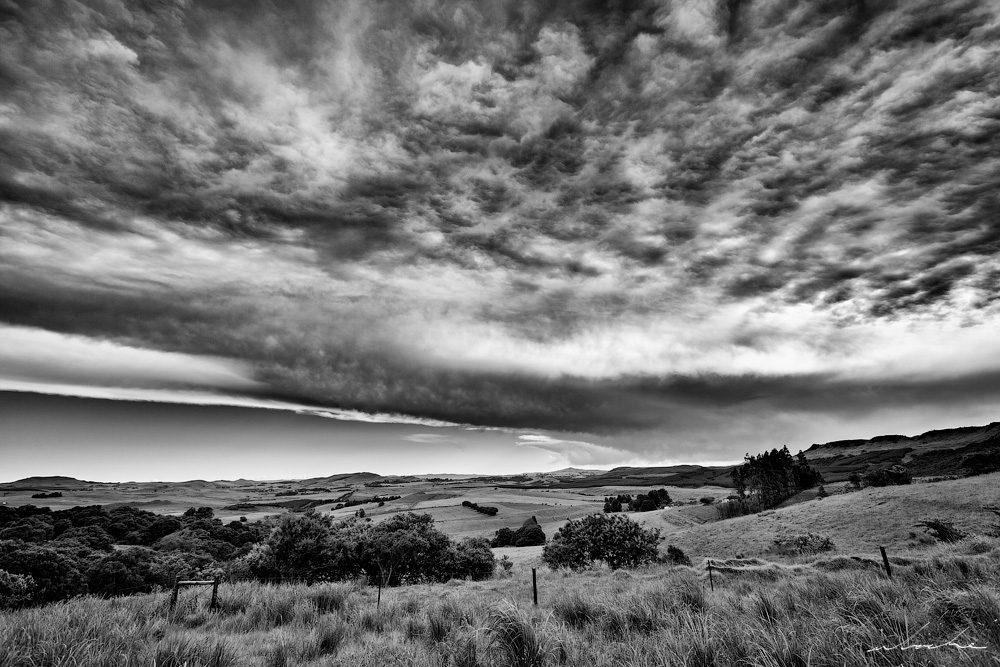 Black and white of Boston Valley in KZN Midlands beneath a dramatic sky