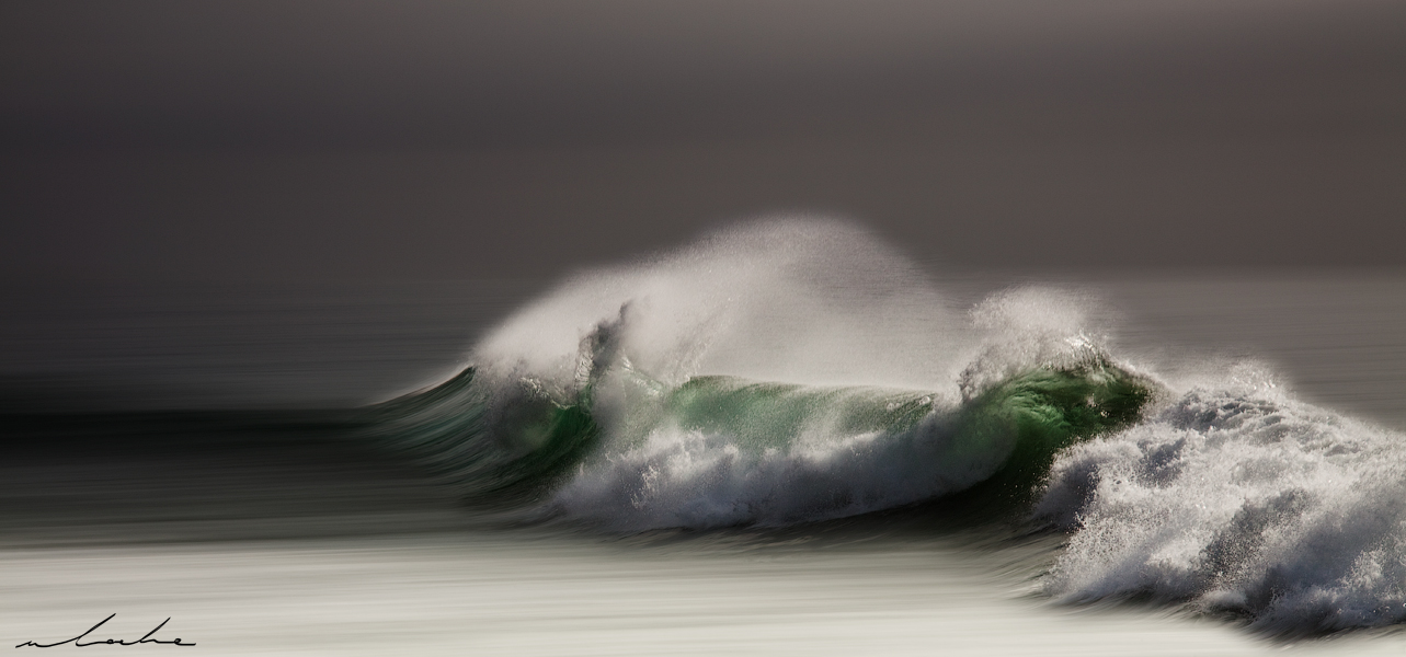 A moody colour photograph of a wave breaking