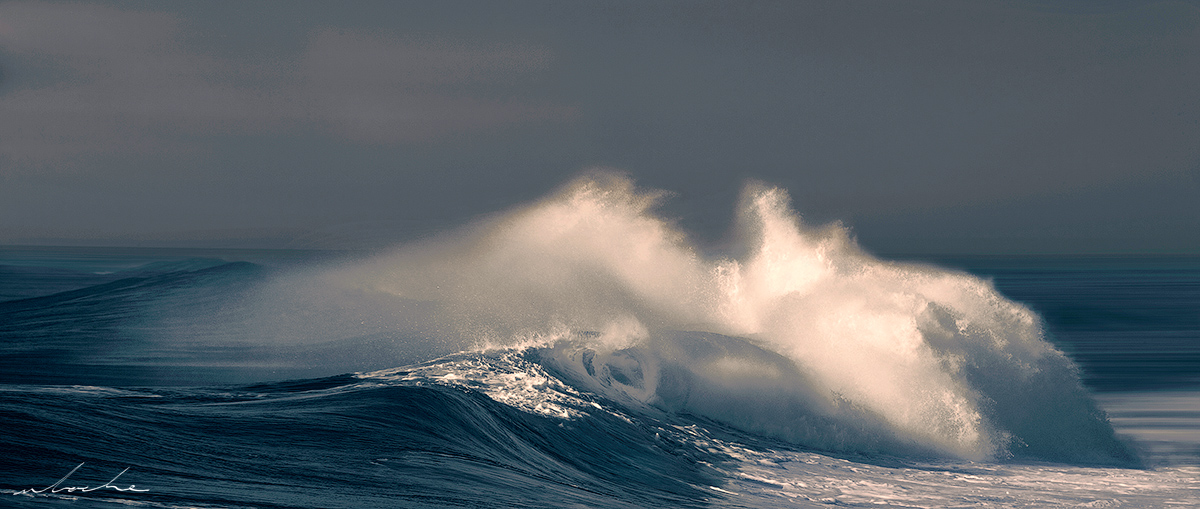 A toned photograph of a single wave rolling in towards the beach